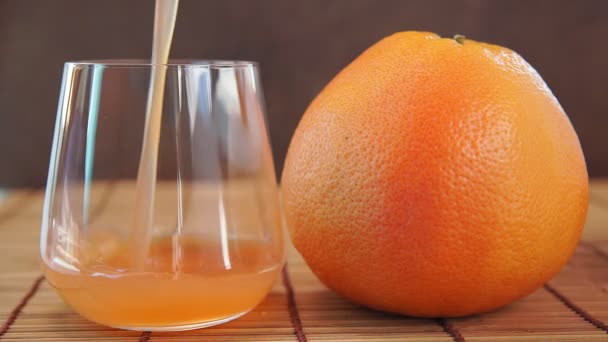 Jus de pamplemousse se déverse dans un verre et pamplemousse frais. Vitamine d'agrumes . — Video