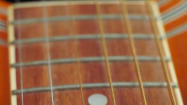 Brown wooden acoustic guitar and part of the neck and strings close up macro — стоковое видео