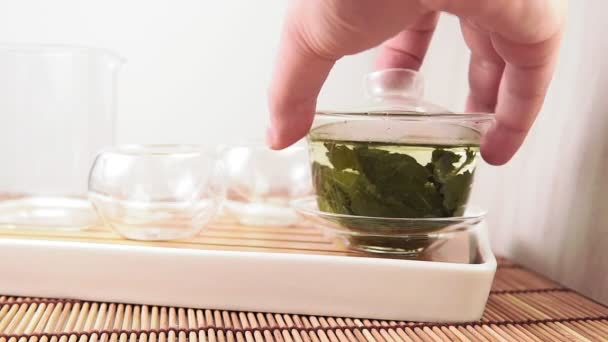 Vierte té verde chino de una tetera de vidrio en una pequeña taza — Vídeos de Stock