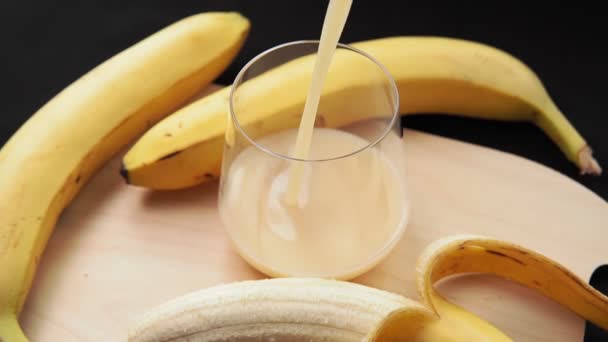 Банановый сок наливается в стакан. Свежие фрукты, избирательная концентрация. Здоровое питание — стоковое видео