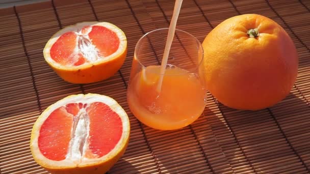 Сок грейпфрута разрядился в стакан. Витаминный сок цитрусовых в прозрачном стакане . — стоковое видео