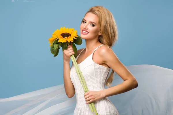 Portrait de jolie femme d'été avec tournesol à la main sur fond bleu — Photo