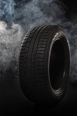 Car tires close-up Winter wheel profile structure on black background with smoke clipart