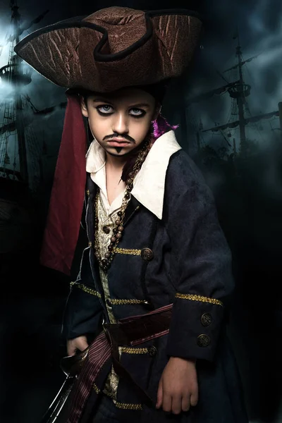 Злий хлопець у піратському костюмі. Він стоїть на тлі корабля — стокове фото
