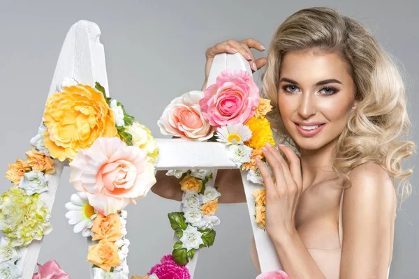 Fijne blonde vrouw met bloemen witte ladder — Stockfoto