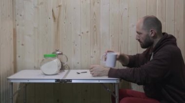 the guy drinks from the mug, puts it on the table, then gets up and leaves