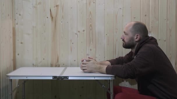 Um cara em um vestido vermelho bebendo chá de uma caneca branca e olha para a frente para o quarto — Vídeo de Stock