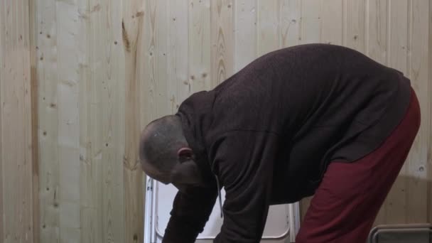 Dans la chambre un gars en vêtements rouges recueille une table pliante — Video