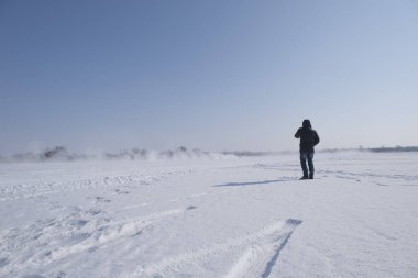 Spassk-Dalny, Primorsky Krai, Rusya-2020 Şubat 8: Bir kişi karda yol alan bir arabayı izliyor, güneşli bir gün, bulutsuz bir gökyüzü, pürüzsüz kar.