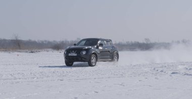 Spassk-Dalny, Primorsky Krai, Rusya-2020 Şubat 8: Karlı yolda donmuş gölde ağaçların arka planına karşı siyah araba sürüyor, sağdan sola