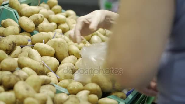 Las manos femeninas ponen papas maduras en la bolsa de plástico transparente. Mujer elige patatas maduras añade al paquete. Compras y concepto de personas. Imágenes de vídeo en stock . — Vídeos de Stock