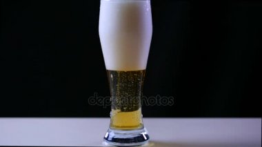 Bira bardağına siyah arka plan üzerine yağıyor. Bubbles ve köpük bira cam çabuk. Köpük bardak bira kayar