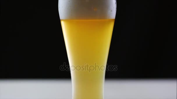 Beer is pouring into glass on black background. — Stock Video