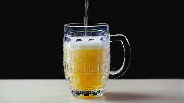 La bière est versée dans le verre sur un fond noir. La mousse glisse rapidement à travers le verre. Mousse et bulles de bière extrêmement grandes. Tasse pleine bière ambre sur fond noir. Mouvement lent . — Video