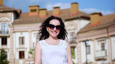 Kameraya gülümseyen güzel beyaz esmer kadın. Ağır çekim, rüzgarda saç. Gözlüklü kadın.