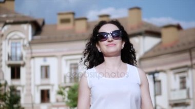 Mutlu bir kadın saçları rüzgarda ayarlar görünüyor ve kamera için de geçerli. Ağır çekim. Beyaz elbise gülümsüyor, genç güzel esmer rahatlatır ve hayat sahiptir.