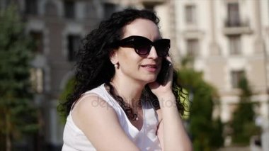 Açık havada Evet güzel bir kadın. Genç bir anne sokakta konuşuyor. O gülümsüyor ve küçük bir çocuk arabasındaki bebek arka planda görebilirsiniz. Gözlüklü bir kadın. Ağır çekim.