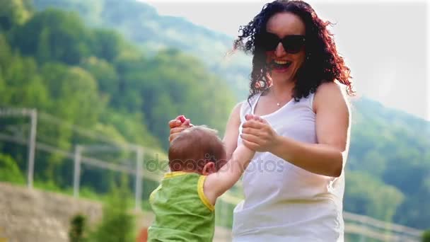 Mama bawi się z dzieckiem. Mama całuje i spinów synka w parku w wolnym tempie. — Wideo stockowe