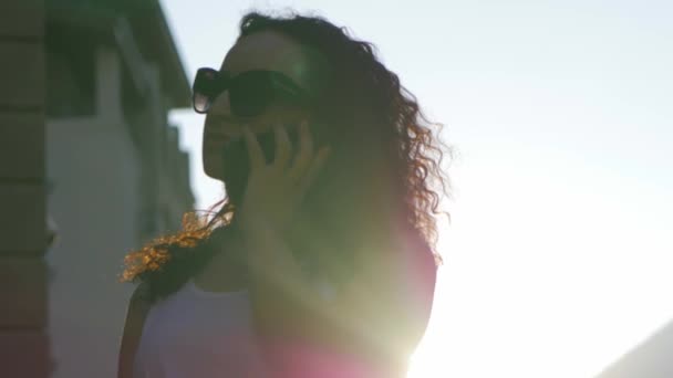 Belle femme parlant au téléphone à l'extérieur. Une femme avec des lunettes. Mouvement lent . — Video