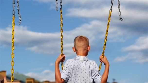 Träume, Sommer. Die Familie genießt den Sommer, geht spazieren. Der Junge reitet auf einer Schaukel. Langsame Mücke. — Stockvideo