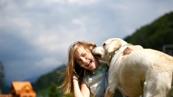 Une adolescente parle au téléphone et joue avec son chien préféré dans le parc. C'est un ami dévoué . — Video