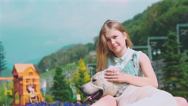 Una adolescente abraza a su perro en el parque. El perro lame y besa a la niña.. Una adolescente está jugando con su perro favorito en el parque. Es un amigo devoto del hombre. . — Vídeo de stock