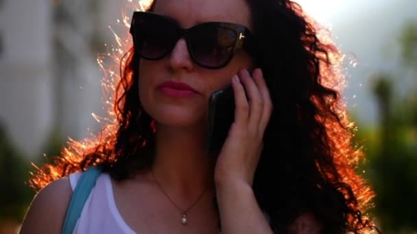 Hermosa mujer hablando por teléfono al aire libre. Una joven madre está hablando en la calle. Una mujer con gafas. Movimiento lento . — Vídeos de Stock