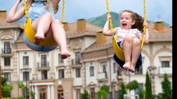 Les petites filles font une balançoire. Deux petites sœurs profitent de la vie sur les balançoires . — Video