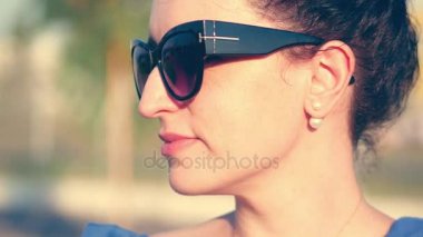 Yakın çekim portre güneşe bakar ve onu gözlük yansıma ona bakmak ve hangi doğası görebilirsiniz bir kadının siyah gözlük seviyor. 4k.
