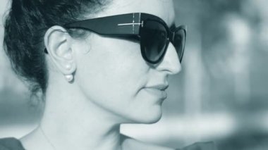 Yakın çekim portre güneşe bakar ve onu gözlük yansıma ona bakmak ve hangi doğası görebilirsiniz bir kadının siyah gözlük seviyor. 4k.