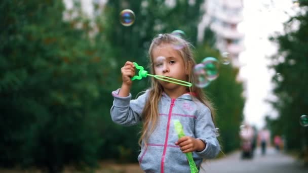 Meisje met blauwe ogen in een pak, spelen met zeepbellen, buitenshuis, plezier. Slow motion — Stockvideo