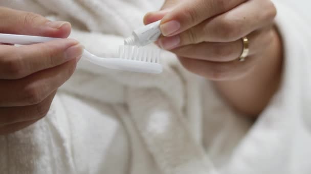 A bela morena estende a base da pasta de dentes em uma escova de dentes. 4k . — Vídeo de Stock