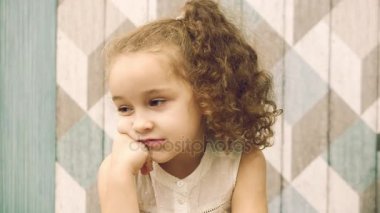 Kız bebek düşünceli bir yana, yana doğru gözleri ile bakarak görünüyor. Çocuk, çocuk, duygular.