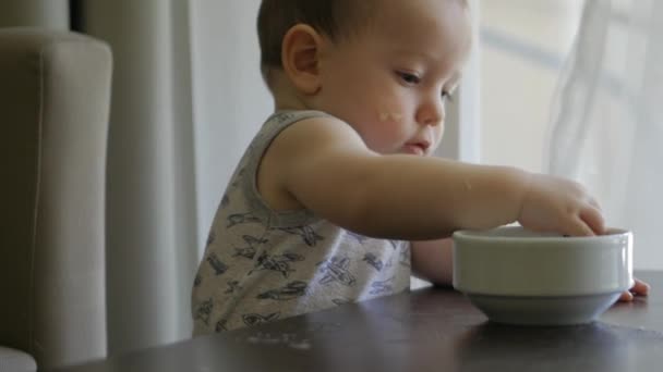 En liten pojke äter gröt själv. 4k, — Stockvideo