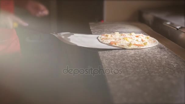 Повар кладет пиццу на лопату, чтобы положить пиццу в духовку. 4K . — стоковое видео