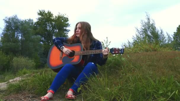 Een mooi meisje, omarmd door een creatieve inspanning en geïnspireerd door een boslandschap met uitzicht op de rivier en de aard van het gewoonweg verbluffend, pakt een nieuwe melodie voor een nieuw lied. 4 k. handen close-up — Stockvideo