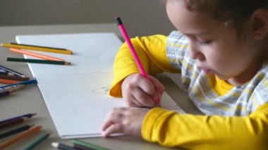 Küçük şirin küçük kız evine renkli kalemler ile çizer. 4k.