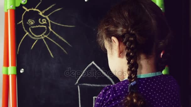 Ένα μικρό κορίτσι αντλεί ένα σπίτι των ονείρων για ένα malbert με χρωματιστά μολύβια. — Αρχείο Βίντεο