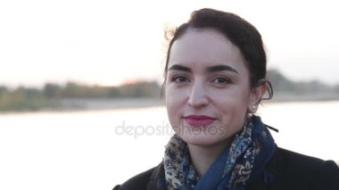 Genç kadın kameraya bakıyor ve gülümsüyor.