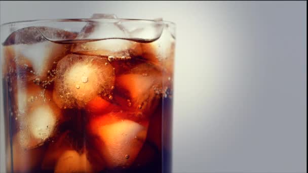 Cola dengan latar belakang es batu. Cola dengan es dan gelembung di kaca. Penutup Soda. Makanan latar belakang. Stok full HD video footage 4K — Stok Video