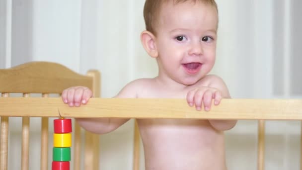 Il bambino affascinante nella culla ride e si muove intorno alla culla e allo stesso tempo cerca di farla ridere. 4k . — Video Stock