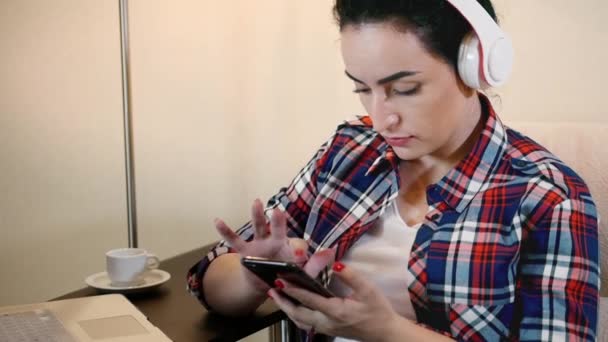 Mujer de belleza escuchando música en los auriculares y escribiendo en el teléfono inteligente . — Vídeos de Stock