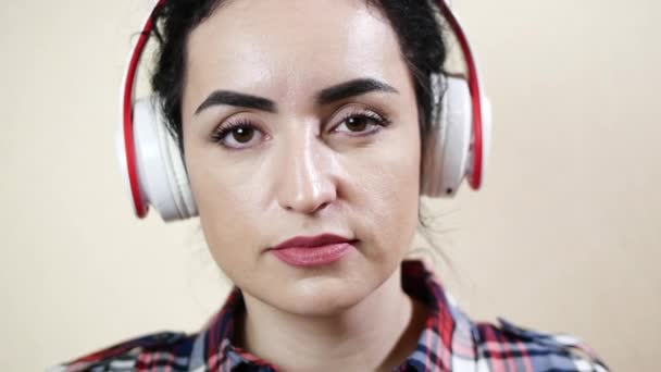 Belleza mujer escuchando música con auriculares y mirando a la cámara sonriendo — Vídeos de Stock