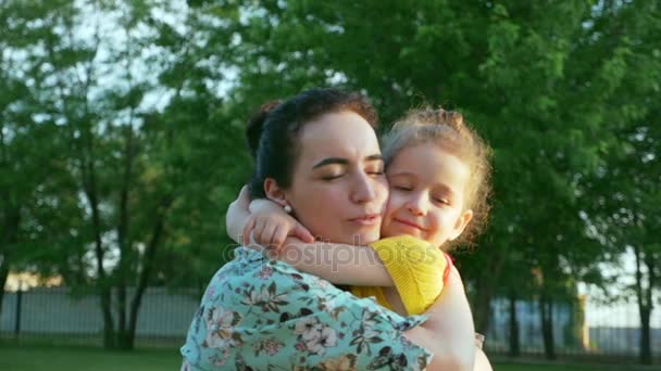 Une jeune mère calme et étreint sa petite fille lors d'une promenade dans le jardin. Enfants . — Video