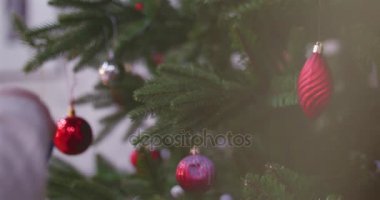 Noel süsler Noel ışıkları ile bir ağaç üzerinde asılı. Küçük bir kızın elleri yakın çekim bir Noel ağacı süsleyin. 4k