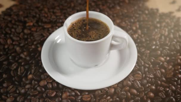 Šálek kávy a kávových zrn. Bílý hrnek odpařovací kávu na stůl s pražených bobů. Super Slow Motion kávu nalít.