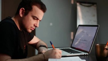 Ofiste bir yakışıklı genç iş adamı şafakta Kripto borsa analiz yapıyor kar ve zarar hesaplar.