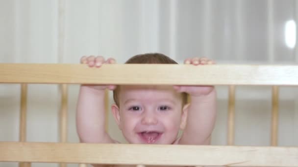 Uma criança encantadora em um berço ri e bate palmas. 4k . — Vídeo de Stock