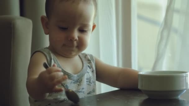 A little boy eats porridge himself. 4K, — Stock Video