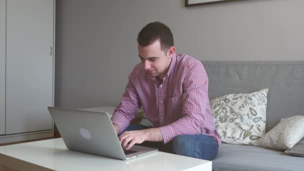 Een persoon werkt vanuit huis met behulp van de boven- en trackpad. Jonge zakenman zittend aan tafel, koffie drinken, werk op computer. 4k — Stockvideo